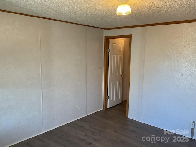 empty room with crown molding, a textured ceiling, and dark hardwood / wood-style flooring