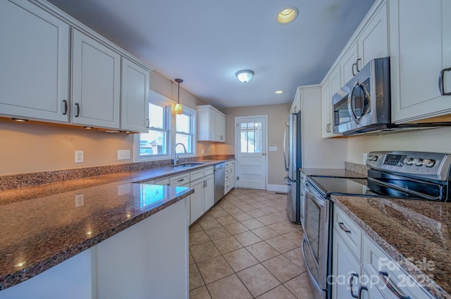 kitchen featuring dark stone countertops, pendant lighting, sink, white cabinetry, and stainless steel appliances