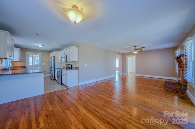 kitchen featuring light wood-type flooring, sink, stainless steel appliances, and white cabinetry