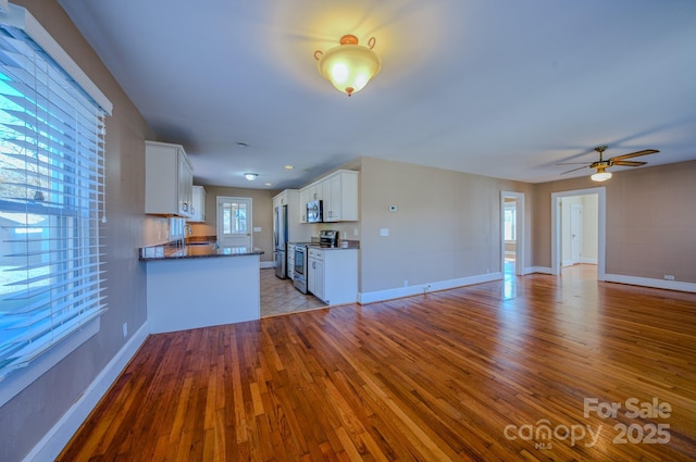 kitchen featuring white cabinetry, light hardwood / wood-style floors, kitchen peninsula, ceiling fan, and stainless steel appliances