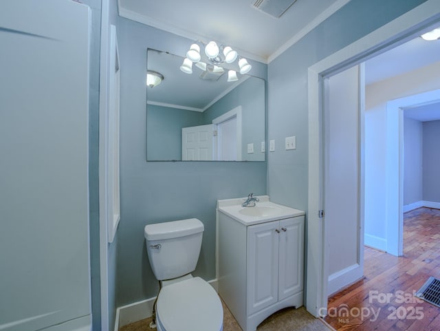 bathroom featuring toilet, hardwood / wood-style floors, ornamental molding, a chandelier, and vanity