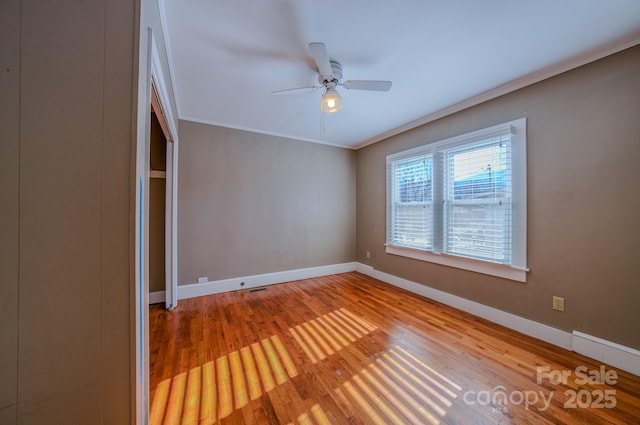 empty room featuring hardwood / wood-style flooring, ornamental molding, and ceiling fan