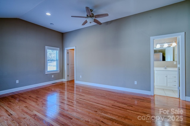 unfurnished bedroom with ensuite bathroom, ceiling fan, light wood-type flooring, vaulted ceiling, and sink