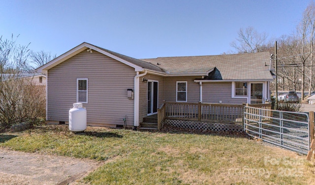 rear view of house featuring a wooden deck and a lawn