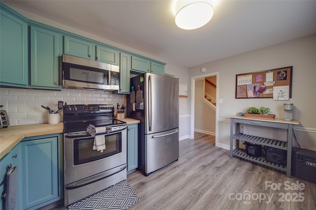 kitchen featuring butcher block countertops, backsplash, stainless steel appliances, and light hardwood / wood-style floors