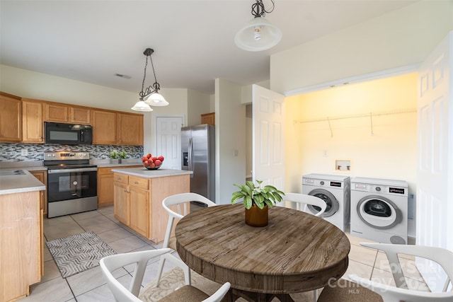 kitchen with backsplash, a kitchen island, washing machine and dryer, hanging light fixtures, and stainless steel appliances