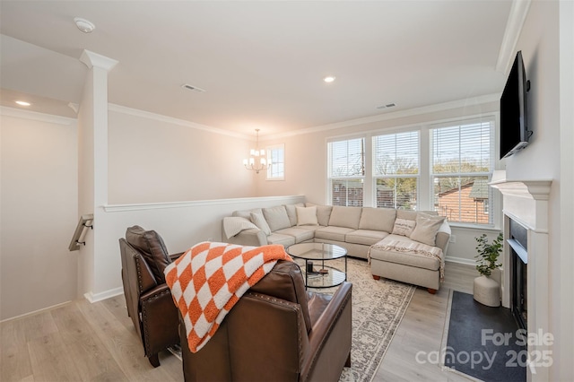 living room featuring ornamental molding, a chandelier, and light hardwood / wood-style floors