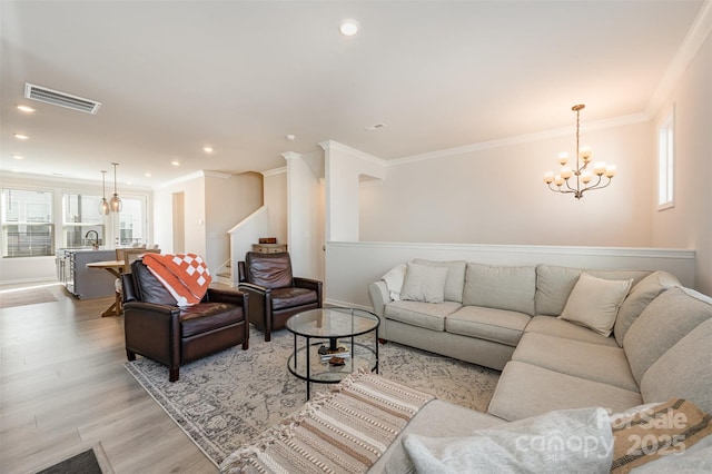 living room with an inviting chandelier, crown molding, and light wood-type flooring