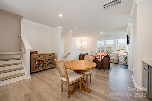 dining room with an inviting chandelier, crown molding, and light hardwood / wood-style flooring