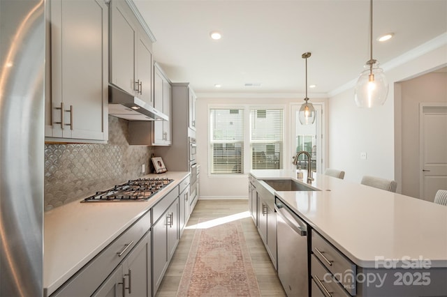 kitchen with stainless steel appliances, gray cabinets, sink, and a center island with sink