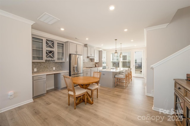 kitchen with gray cabinets, a breakfast bar, appliances with stainless steel finishes, hanging light fixtures, and a kitchen island