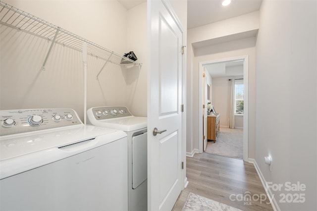 laundry room featuring washer and clothes dryer and light hardwood / wood-style flooring