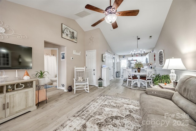 living room featuring ceiling fan with notable chandelier, light hardwood / wood-style floors, and high vaulted ceiling