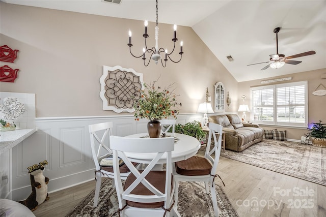 dining space featuring vaulted ceiling, ceiling fan with notable chandelier, and hardwood / wood-style floors