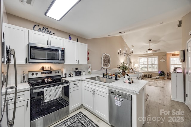 kitchen with kitchen peninsula, sink, white cabinetry, decorative backsplash, and stainless steel appliances