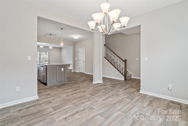 unfurnished living room featuring light hardwood / wood-style floors, sink, and a chandelier