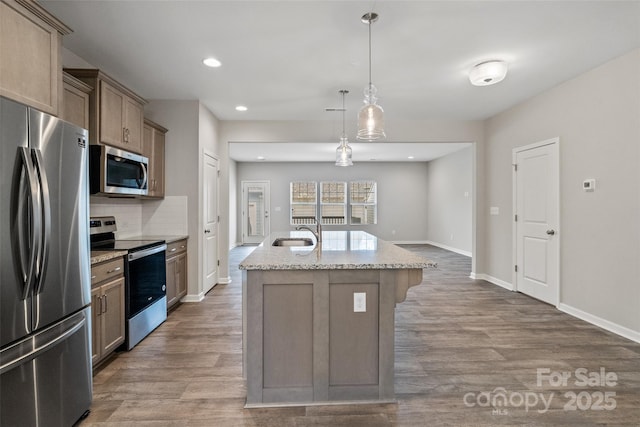 kitchen with pendant lighting, tasteful backsplash, light stone counters, a kitchen island with sink, and stainless steel appliances