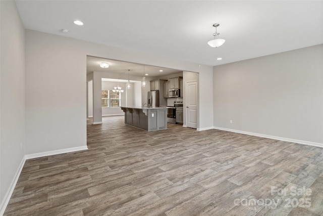 unfurnished living room featuring hardwood / wood-style flooring and an inviting chandelier