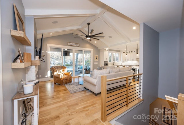 living room featuring light wood-type flooring, ceiling fan, and lofted ceiling with beams