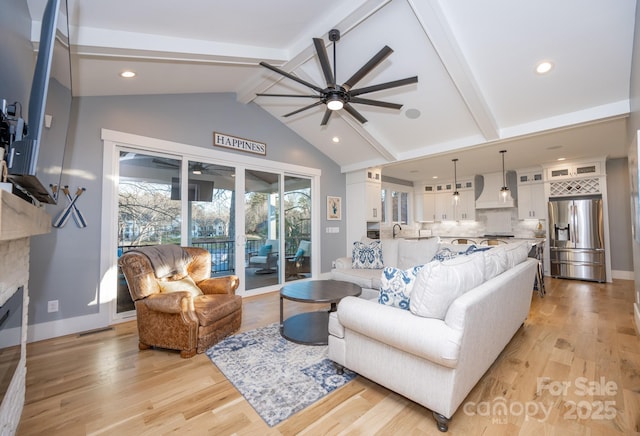 living room with a fireplace, ceiling fan, light hardwood / wood-style floors, and vaulted ceiling with beams