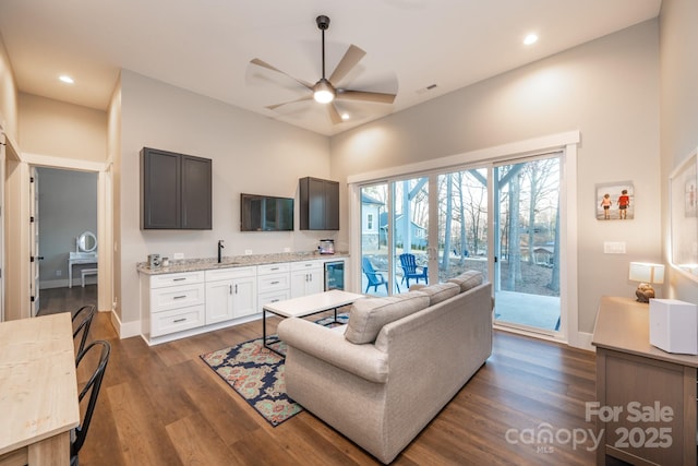 living room with ceiling fan, dark wood-type flooring, sink, and beverage cooler