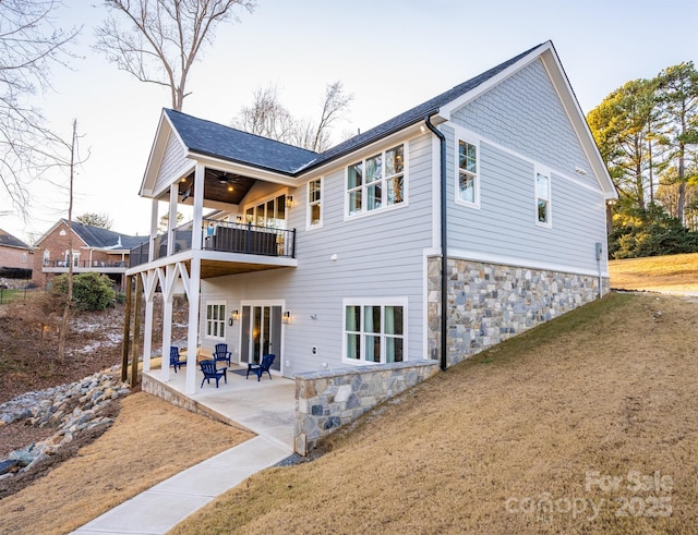 rear view of property with a balcony, a patio area, and a yard