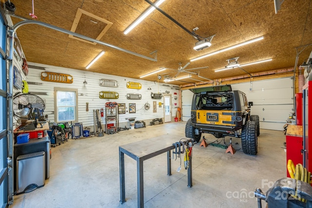 garage with wood walls, a garage door opener, and a workshop area