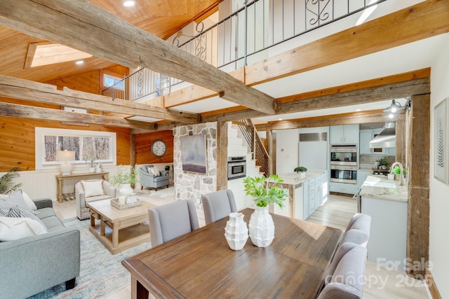 dining room featuring high vaulted ceiling, wooden ceiling, beam ceiling, and wood walls