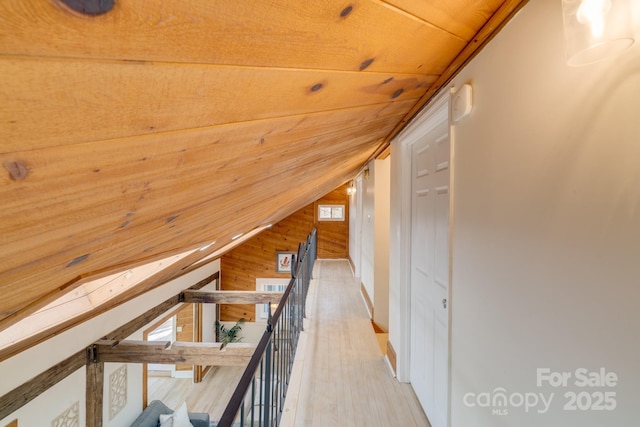 corridor featuring hardwood / wood-style flooring, wooden walls, vaulted ceiling, and wooden ceiling