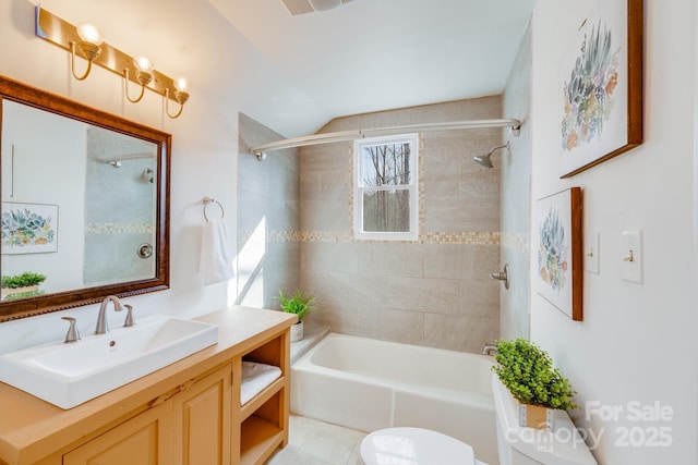 full bathroom featuring vanity, tiled shower / bath, and toilet