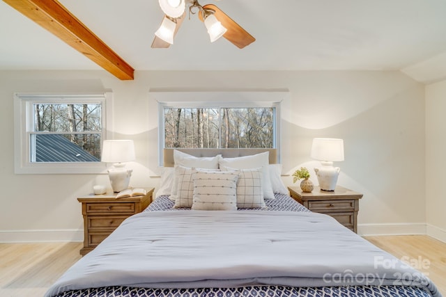 bedroom with ceiling fan, beamed ceiling, and light wood-type flooring