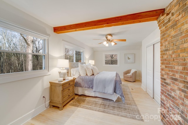 bedroom with beamed ceiling, ceiling fan, light hardwood / wood-style floors, and a closet