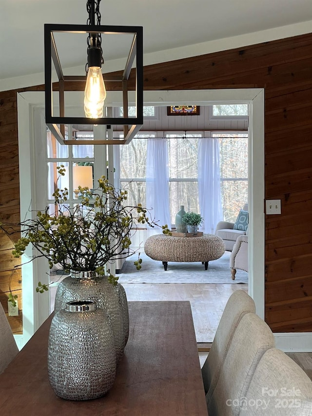 dining space with an inviting chandelier and wood walls