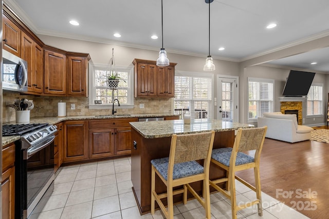 kitchen featuring a stone fireplace, sink, appliances with stainless steel finishes, a kitchen island, and backsplash