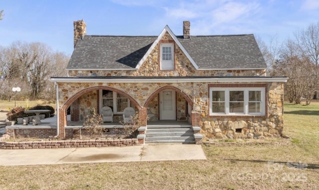 tudor-style house with covered porch and a front lawn