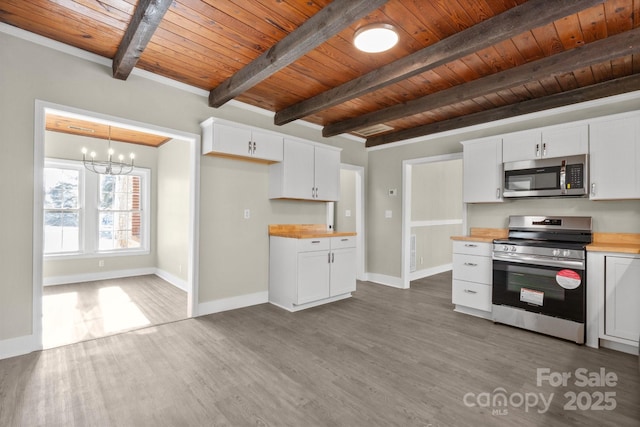 kitchen with decorative light fixtures, appliances with stainless steel finishes, wood counters, and white cabinetry