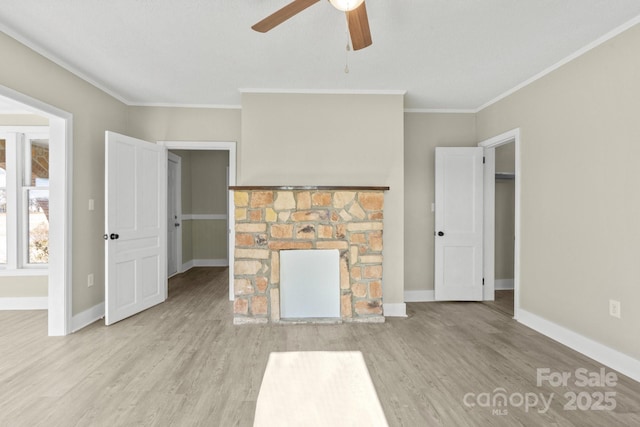 unfurnished living room featuring ceiling fan, crown molding, light hardwood / wood-style flooring, and a stone fireplace