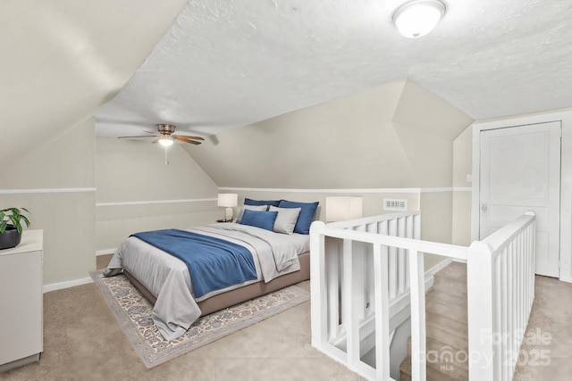 bedroom with a textured ceiling, ceiling fan, lofted ceiling, and light carpet