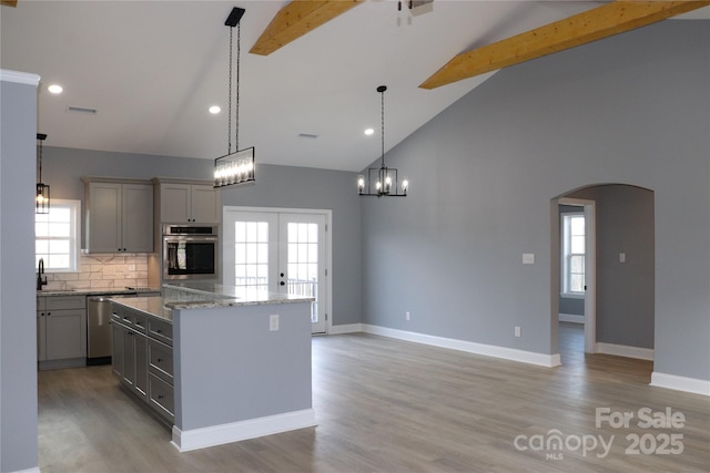 kitchen with a center island, high vaulted ceiling, hanging light fixtures, gray cabinets, and stainless steel appliances