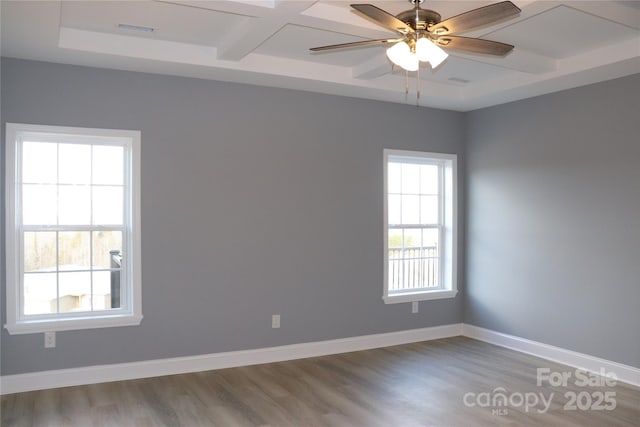 empty room featuring beamed ceiling, coffered ceiling, and a wealth of natural light