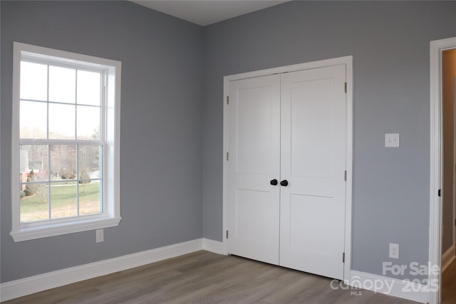 unfurnished bedroom featuring a closet, wood-type flooring, and multiple windows