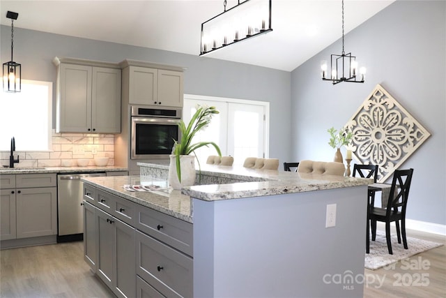 418 Huntington Woods St SE, Lenoir, NC 28645 - kitchen with stainless steel appliances, light wood-type flooring, a sink, a chandelier, and gray cabinetry