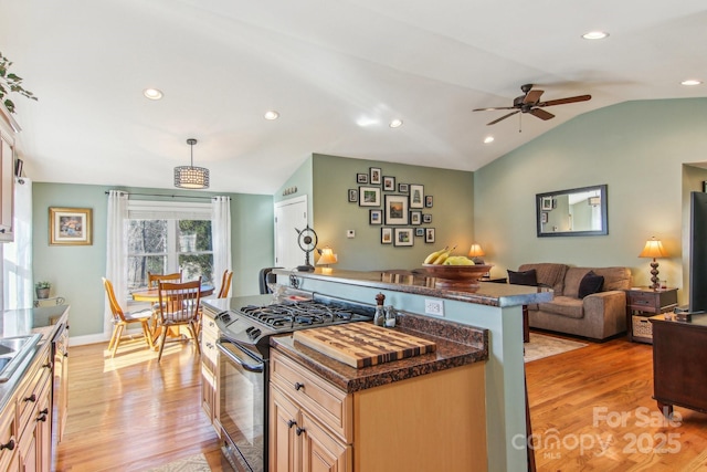 kitchen with appliances with stainless steel finishes, decorative light fixtures, dark stone countertops, vaulted ceiling, and light hardwood / wood-style flooring