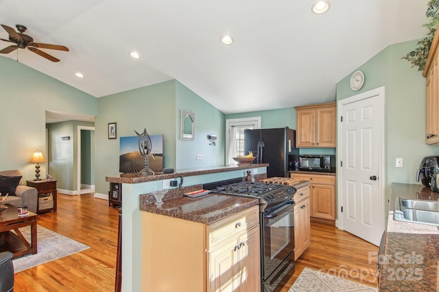 kitchen with black appliances, vaulted ceiling, light brown cabinets, and light hardwood / wood-style floors