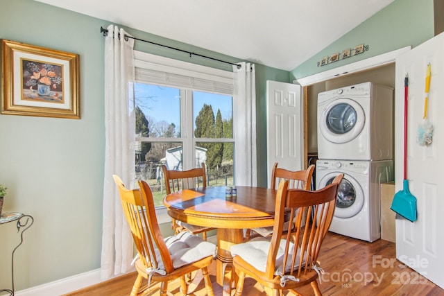 dining area featuring light hardwood / wood-style floors, lofted ceiling, and stacked washing maching and dryer