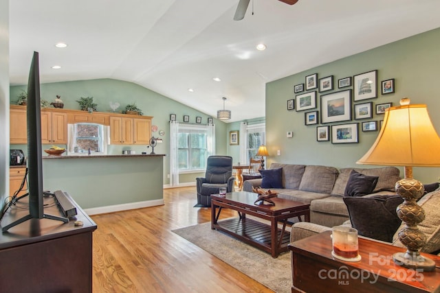 living room with ceiling fan, lofted ceiling, and light hardwood / wood-style floors