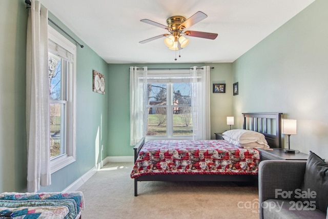 bedroom featuring ceiling fan, light colored carpet, and multiple windows