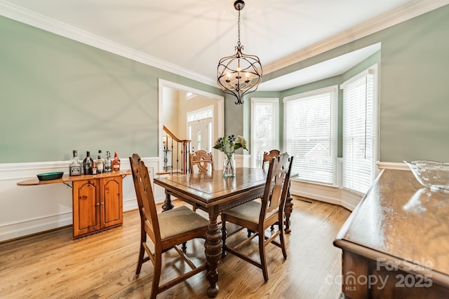 dining space featuring ornamental molding, light hardwood / wood-style floors, and a notable chandelier