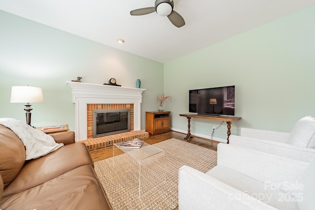 living room with hardwood / wood-style flooring, ceiling fan, and a brick fireplace