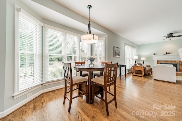 dining room with a brick fireplace, a wealth of natural light, and light hardwood / wood-style floors